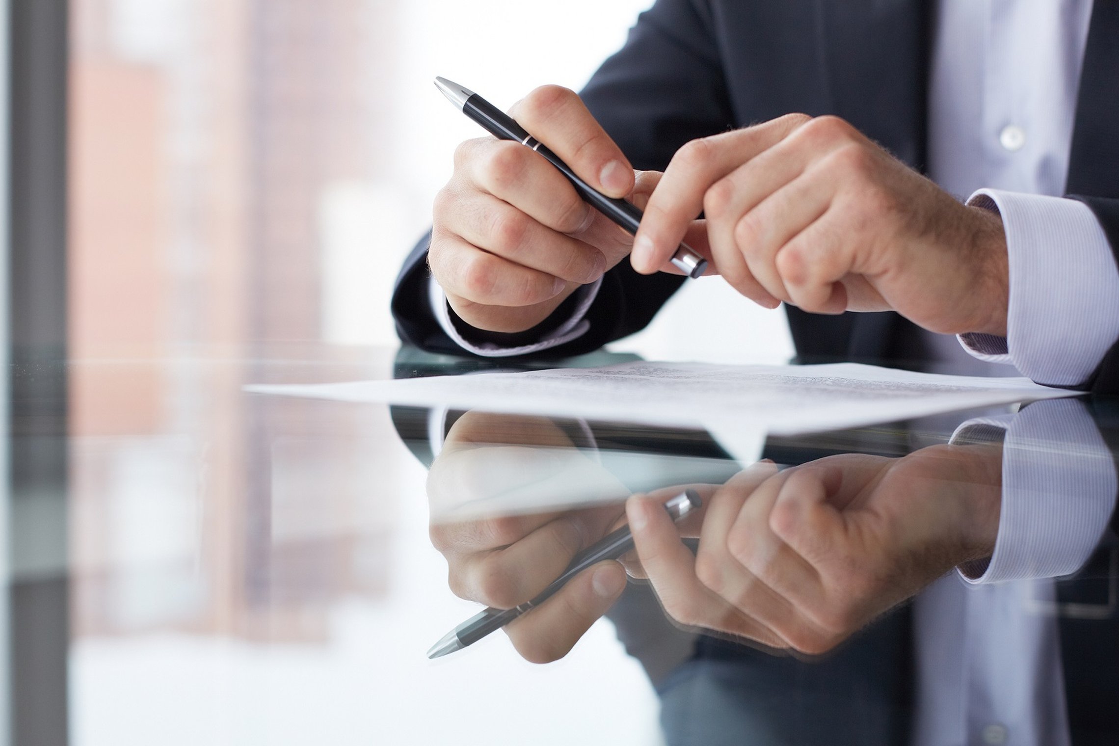 Close-up of male hands with pen over document