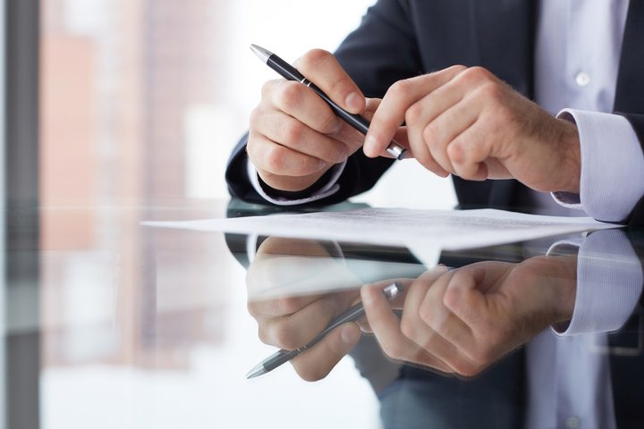 Close-up of male hands with pen over document
